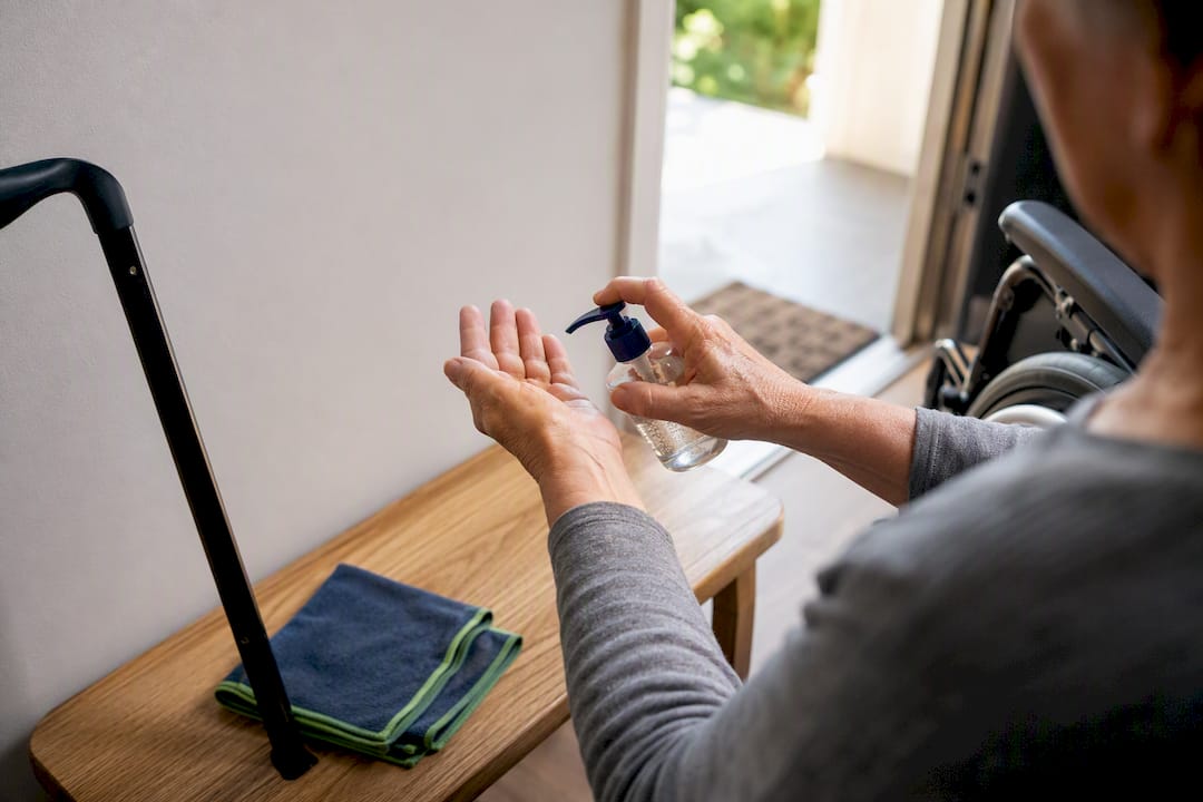 Person sanitizing hands beside mobility equipment